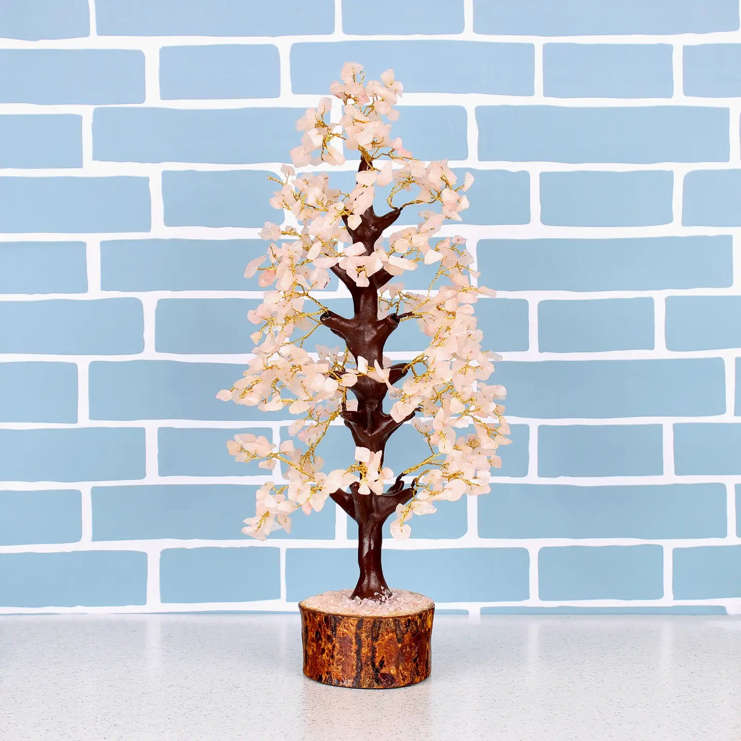 "Rose Quartz Crystal Tree with 500 beads in wooden base on white counter top with blue brick background"