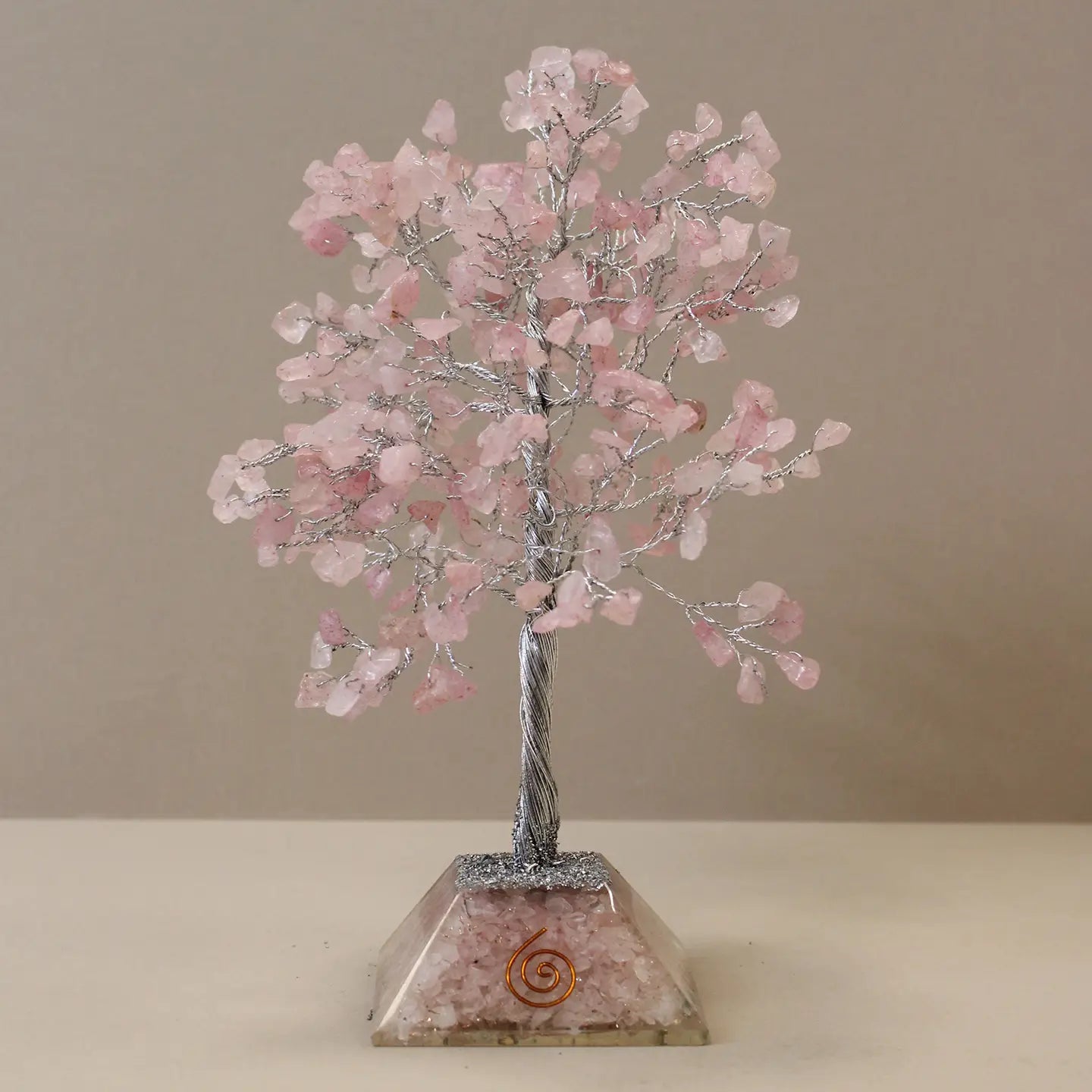 "Rose Quartz Crystal Tree 320 pink beads in orgonite base on beige countertop with taupe background"