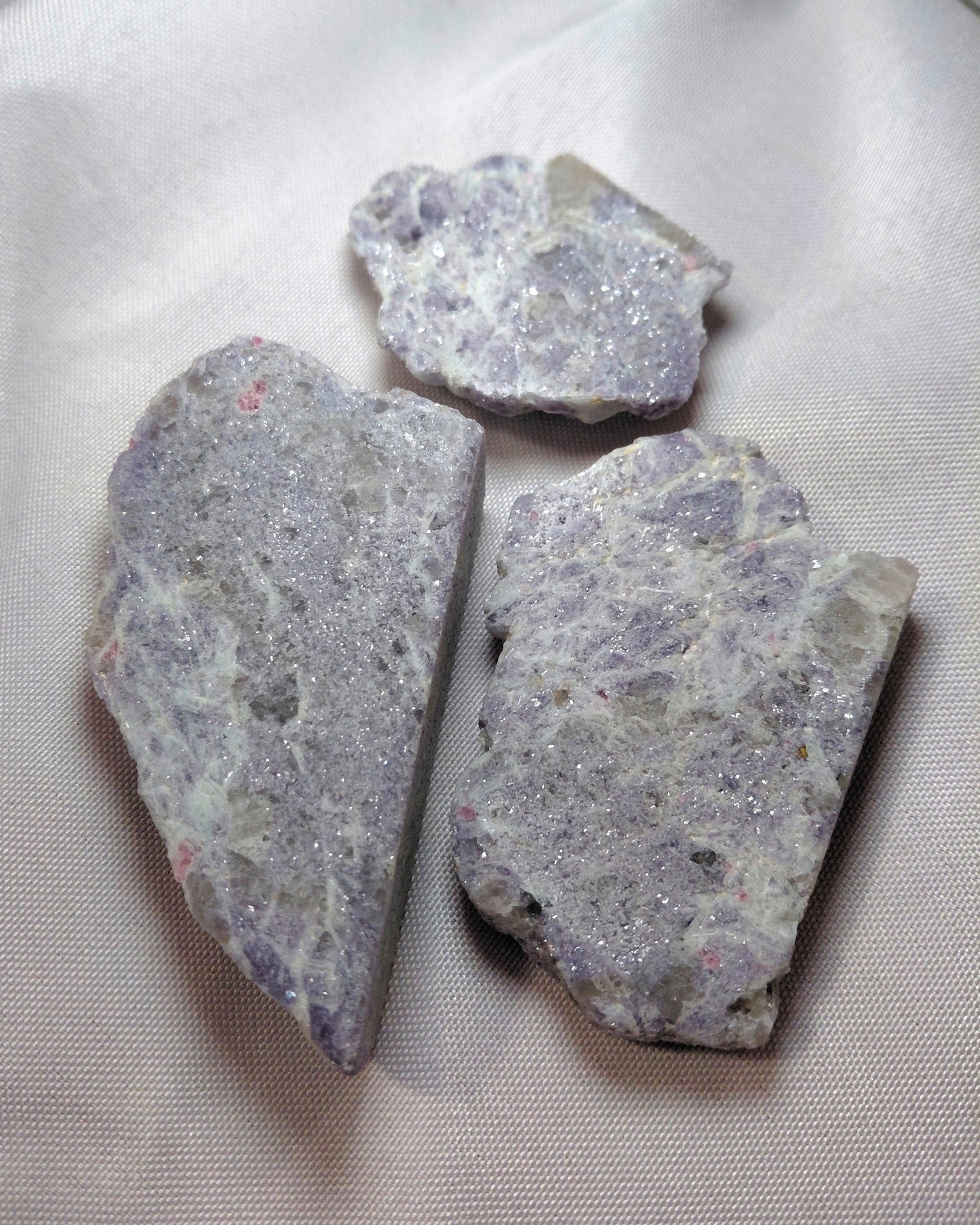 Three pieces of purple and gray stone on a white fabric background